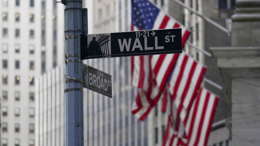 FILE - The Wall St. street sign is framed by the American flags flying outside the New York Stock exchange, Friday, Jan. 14, 2022, in the Financial District. Stocks are off to a mixed start on Wall Street Friday, March 25, wrapping up a bumpy week with more uncertainty about where to go next. (AP Photo/Mary Altaffer, File)