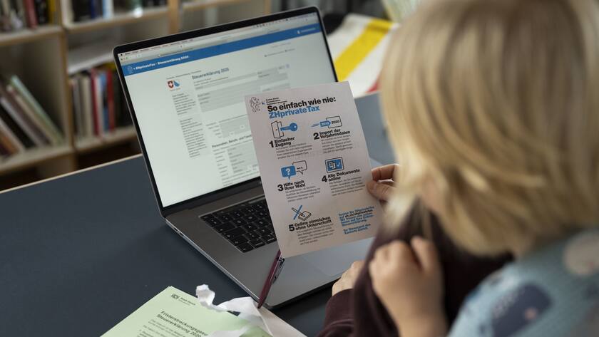 Eine Frau in Anwesenheit ihres Sohnes studiert in ein Infoblatt zur Einreichung Online-Steuererklaerung 2020 (ZHprivate Tax) des Kanton Zuerich, fotografiert am 25. Januar 2021 in Zuerich. (KEYSTONE/Christian Beutler)