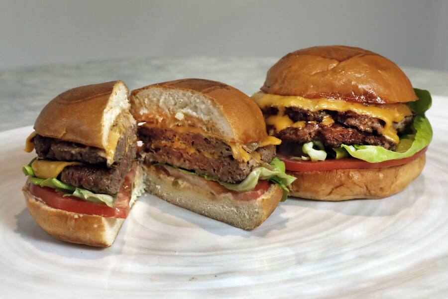 An Original Impossible Burger, left, and a Cali Burger, from Umami Burger, are shown in this photo in New York, Friday, May 3, 2019. A new era of meat alternatives is here, with Beyond Meat becoming the first vegan meat company to go public and Impossible Burger popping up on menus around the country. (AP Photo/Richard Drew)