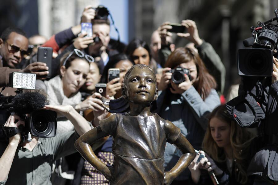 People stop to photograph the "Fearless Girl" statue, Wednesday, March 8, 2017, in New York. The statue was installed by investment firm State Street Global Advisors. An inscription at the base reads, "Know the power of women in leadership. She makes a difference." (AP Photo/Mark Lennihan)