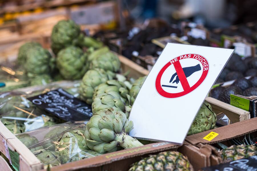 A sign says 'Do not touch' as artichokes lie on a table at the Annecy market on March 20, 2020 in Annecy, France.