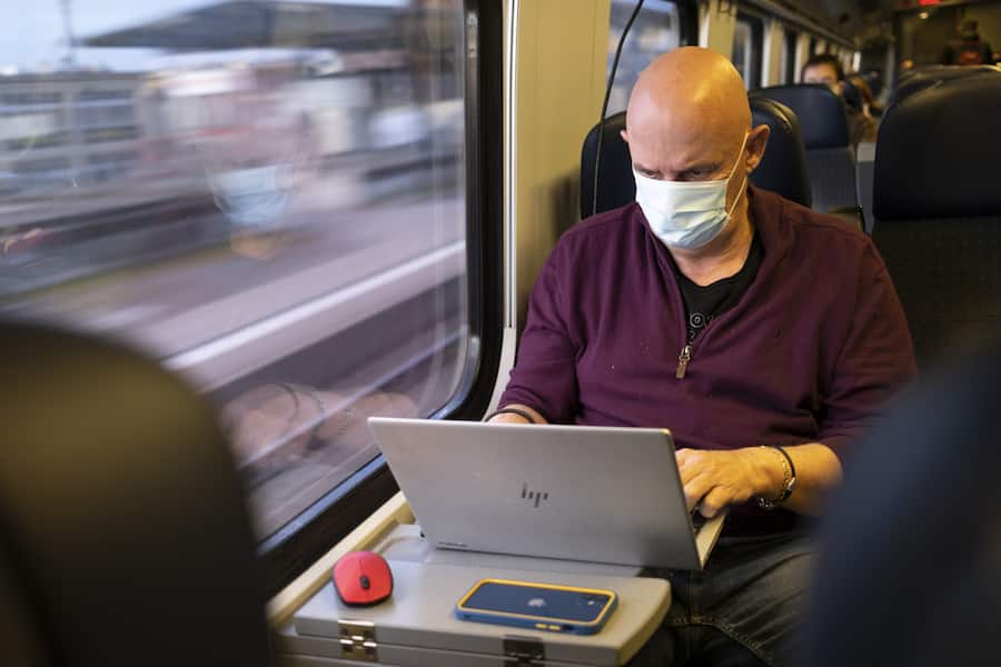 Passenger wearing protective mask works on a laptop as he rides a SBB CFF FFS train during the coronavirus disease (COVID-19) outbreak, in Neuchatel, Switzerland, Tuesday, March 23, 2021. Switzerland as many countries in Europe impose coronavirus restrictions to fight against the spread of coronavirus COVID-19. (KEYSTONE/Laurent Gillieron)