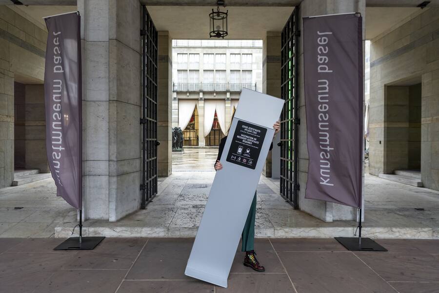 Eine Mitarbeiterin des Kunstmsueums entfernt einen Steller mit den Regeln betreffend des Coronavirus am Eingang des Kunstmuseums in Basel, am Donnerstag, 17. Februar, 2022. Der Bundesrat hebt per Donnerstag fast alle Corona-Massnahmen auf. Dazu gehoert auch die Maskenpflicht in Laeden, Restaurants und am Arbeitsplatz. Restaurants, Veranstaltungen und Kultureinrichtungen sind wieder ohne Covid-Zertifikat zugaenglich. (KEYSTONE/Georgios Kefalas)