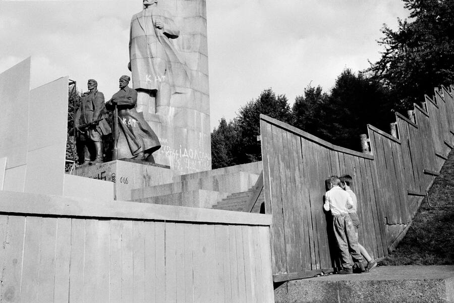 Platz der Oktoberrevolution (heute: Maidan Platz). Zwei Knaben spähen durch ein Loch im Bauzaunaun auf das Denkmal der Grossen Oktoberrevolution mit der Leninstatue. Wenige Tage später wurde das Monument entfernt.