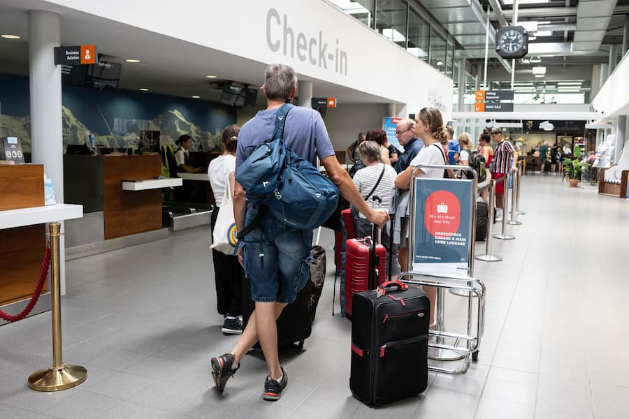 Fluggäste warten am Check-in Schalter in Zürich mit ihrem Gepäck.