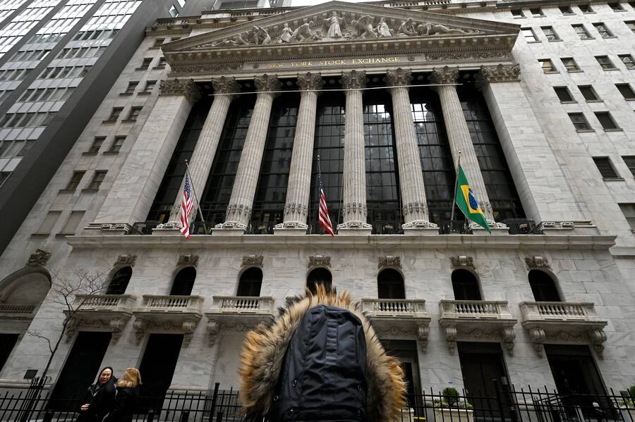 Frau schaut auf das Wall-Street-Gebäude. Man sieht nur ihren Hinterkopf, sie trägt eine Jacke mit Kapuze.