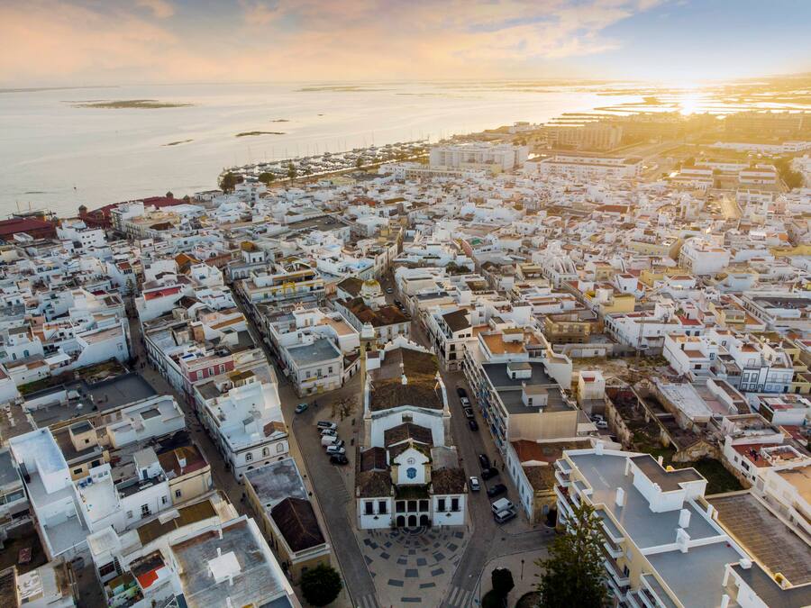 Luftaufnahme von Olhao mit einer Kirche im Vordergrund bei Sonnenuntergang, Algarve, Portugal, Europa