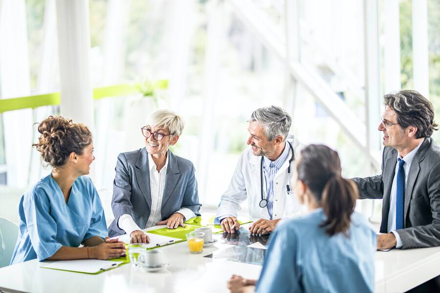 Team of happy doctors and business people communicating while having a meeting at doctor's office in the hospital.