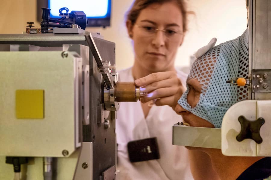 Ein Patient wird von einer Mitarbeiterin des Centre Antoine Lacassagne CAL in Nizza auf die Protonenbestrahlung seines rechten Auges vorbereitet.