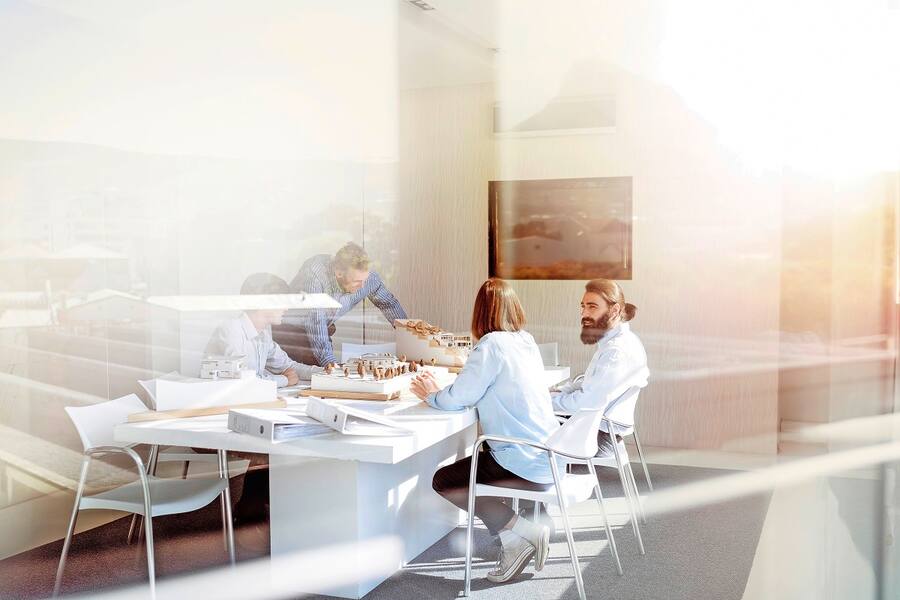 Male and female architects discussing over project in board room seen through glass