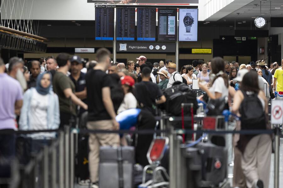 Passengers look at screens informing them of the flight situation, on Friday, 19 July 2024, at the airport Zurich in Kloten, Switzerland. Due to a worldwide IT breakdown, check-in for air travellers and flight operations are severely restricted and most flights are delayed or cancelled. Swiss air traffic control Skyguide is also affected by the IT disruption and has reduced the capacity of Swiss transit traffic as an immediate precautionary measure. (KEYSTONE/Gaetan Bally)