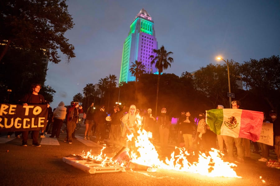 Protesters stand beside a fire amid clashes with law enforcement in the streets surrounding the federal building during a protest following federal immigration operations in Los Angeles, California, on June 8, 2025. Demonstrators torched cars and scuffled with security forces in Los Angeles on June 8, as police kept protestors away from the National Guard troops President Donald Trump sent to the streets of the second biggest US city. (Photo by RINGO CHIU / AFP)