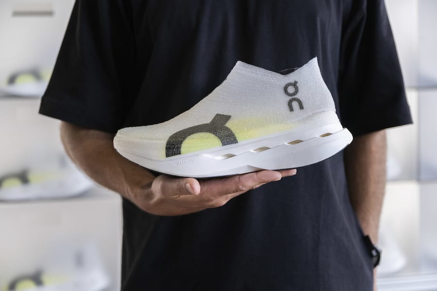 Ein Mann praesentiert einen bespruehten Sportschuh von On, dieser wird mit einem Tintenstrahldrucker bedruckt und anschliessend mit ultravioletten Strahlen fixiert, aufgenommen anlaesslich der Eroeffnung des LightSpray Produktionsstandortes von On, eine vollautomatisierte Schuhproduktion, am Mittwoch, 2. Juli 2025, Zuerich. (KEYSTONE/Ennio Leanza)