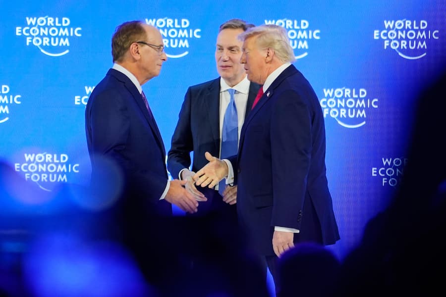 President Donald Trump is welcomed by Forum's President Borge Brende and Forum's Co-Chair Larry Fink on the podium before his speech during the Annual Meeting of the World Economic Forum in Davos, Switzerland, Wednesday, Jan. 21, 2026. (AP Photo/Markus Schreiber)