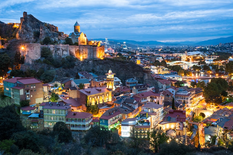 Tbilisi's old town lights up just after sunset, with Narikala Fortress perched high above, Tbilisi, Georgia